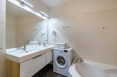 a bathroom with a washing machine and a sink and a tub at Štupartská - Tyn Church View Residence with terrace in Prague