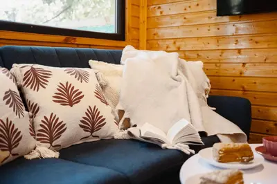 a blue couch with pillows and a book on it at Secret Lake Prag magic place relaxation& wellness in Řehenice