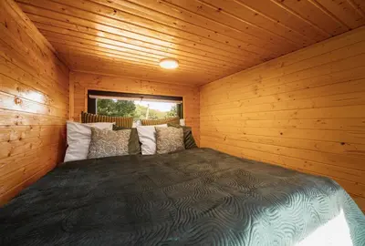 a bedroom with a bed in a wooden cabin at Secret Lake Prag magic place relaxation& wellness in Řehenice