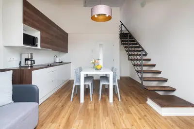 a kitchen and living room with a table and a staircase at Prague Tales Boutique Residence by Dwellfort in Prague