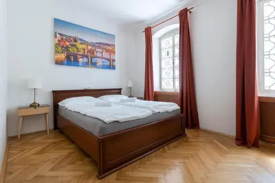 a bedroom with a bed and two windows at Historic Spirit at Studio under the Prague Castle in Prague