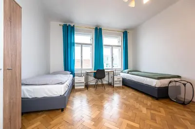 a bedroom with two beds and a window with blue curtains at Apartments Safarikova 18 in Prague