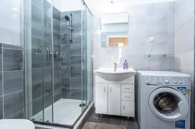 a bathroom with a shower sink and a washing machine at Apartments Safarikova 18 in Prague