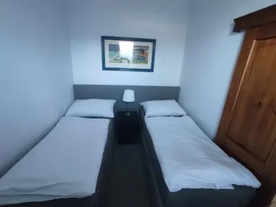 two beds in a small room with a picture on the wall at DoMo apartment in Středokluky