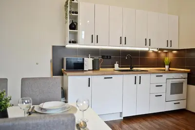 a kitchen with white cabinets and a table with wine glasses at Apartmán u Fontány in Poděbrady