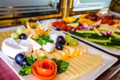 a plate of cheese and vegetables on a table at River hotel KÖNIGSTEIN in Prague