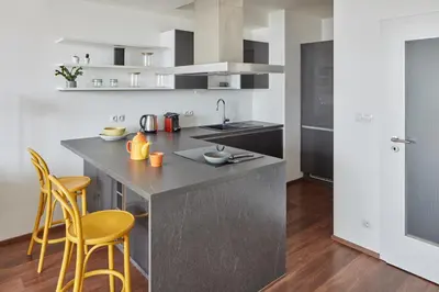 a kitchen with a large island with yellow bar stools at Prague Days - One-bedroom Apartment with Balcony and Garage Parking near the Vltava River in Holešovice in Prague