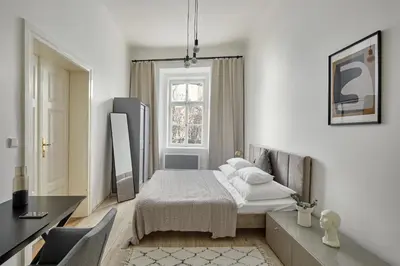 a white bedroom with a bed and a window at Prague Days - Old Town Square Apartments in Prague