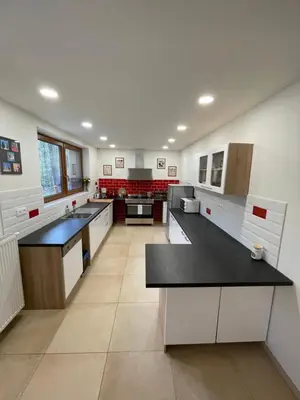 a large kitchen with white cabinets and black counter tops at Kersko Apartments in Hradišťko