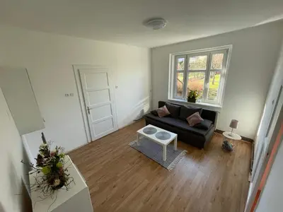 a living room with a black couch and a window at Apartmán Na Polabí in Mělník