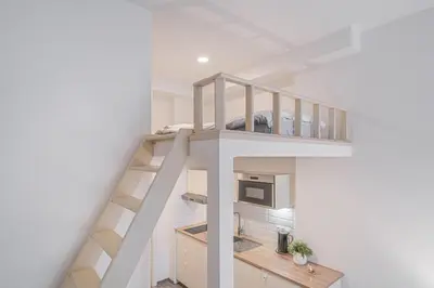 a loft bed in a room with a kitchen at Útulny byt v centru Prahy in Prague