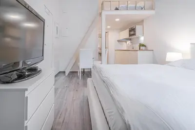 a white bedroom with a bed and a flat screen tv at Útulny byt v centru Prahy in Prague