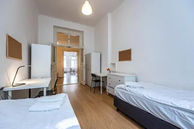 a bedroom with two beds and a desk and a table at Legerova Apartments in Prague