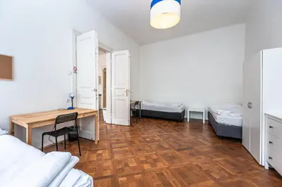 a room with a desk and a table and a room with two beds at Legerova Apartments in Prague