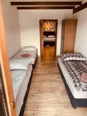 two beds in a room with a wooden floor at Apartmány Županovice in Dobříš