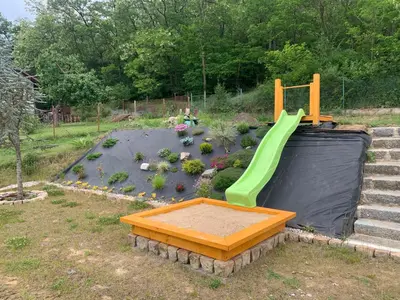 a playground with a green slide in a yard at Apartmány Županovice in Dobříš