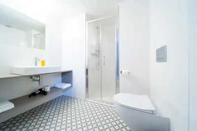 a white bathroom with a toilet and a shower at Karl BY ZEITRAUM in Prague