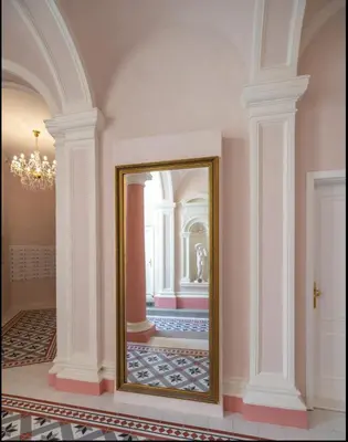 a mirror in a room with white columns at Angelo Roma in Prague