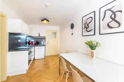 a kitchen with white cabinets and a table with chairs at Celetná - Old Town Residence in Prague