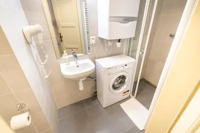a small bathroom with a washing machine and a sink at Celetná - Old Town Residence in Prague