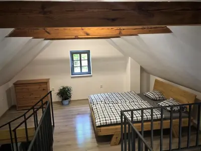 a attic room with a bed and a window at Mezonetový apartmán s terasou na samotě v lese in Vlkava