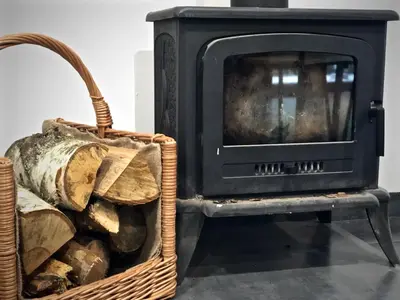 a fireplace and a basket of fire wood at Mezonetový apartmán s terasou na samotě v lese in Vlkava