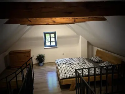 a attic room with a bed and a window at Mezonetový apartmán s terasou na samotě v lese in Vlkava