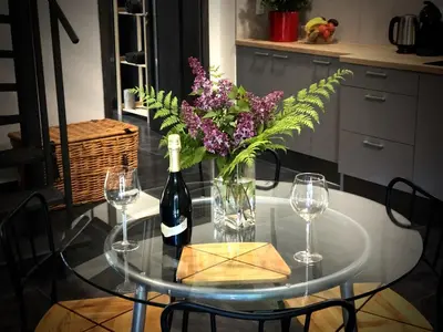 a glass table with a bottle of wine and a vase of flowers at Mezonetový apartmán s terasou na samotě v lese in Vlkava