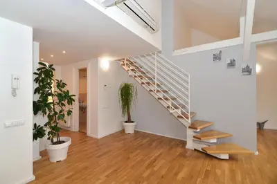 a white hallway with stairs and potted plants at Historic Centre Apartments I in Prague