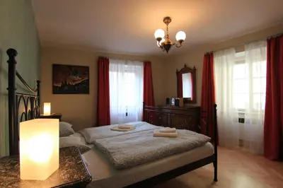 a bedroom with a bed with red curtains and a chandelier at 1 Bed Flat - Sleeps 2 - Wifi in Prague
