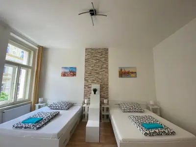 two beds in a room with two windows at Designed apartment next to Vaclav square with terrace and private garage in Prague