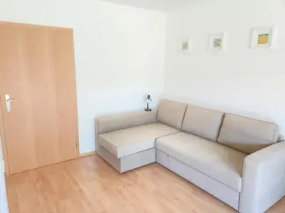 a white couch in a room with a wooden floor at Ubytování U Vrbičky - blízko Prahy in Unhošť