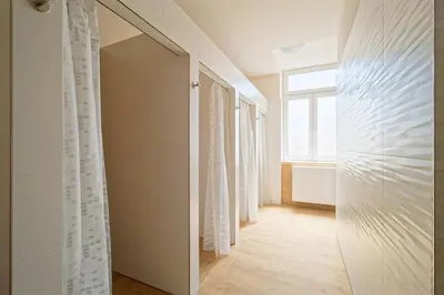 a hallway with a door to a bathroom with a window at Luma Terra Prague Hostel in Prague