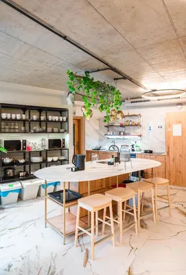a kitchen with a large table and stools at Luma Terra Prague Hostel in Prague