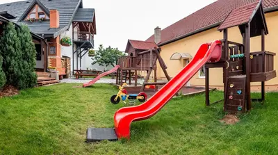 a playground with a red slide in a yard at Penzion U Kapličky in Malá Hraštice