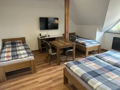a room with two beds and a table and a desk at Penzion U Kapličky in Malá Hraštice
