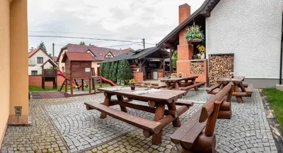 a patio with wooden picnic tables and a playground at Penzion U Kapličky in Malá Hraštice