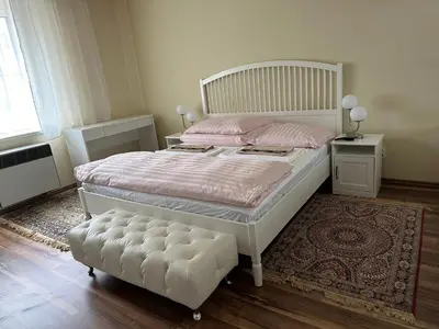 a bedroom with a white bed with pink sheets and a rug at APARTMEN PRAHA in Prague