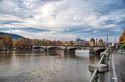 a bridge over a river with people walking across it at Riverside Apartment in Prague