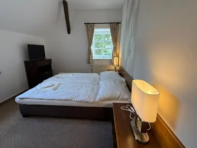 a bedroom with a bed and a desk with a lamp at Bechnerův statek in Lány
