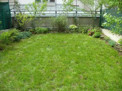 a yard with green grass and flowers and a fence at Garden apartment with garage in central Prague in Prague