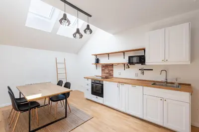 a kitchen with white cabinets and a table and chairs at Stevan Apartment in Prague