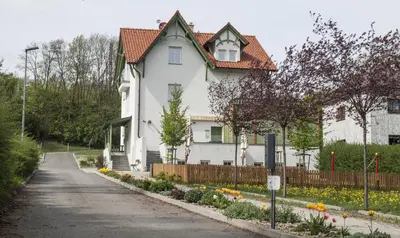 a white house with a fence and flowers at Hotel U Parku in Hořovice
