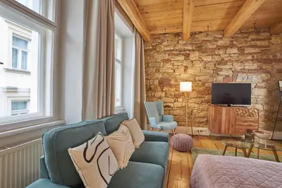 a living room with a blue couch and a tv at Jeruzalémská - Synagogue Apartments in Prague