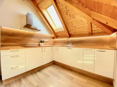 an attic kitchen with white cabinets and a window at Relax Apartment in Prague