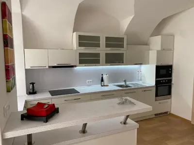 a kitchen with white cabinets and a red item on a counter at Nerudova Apartments in Prague