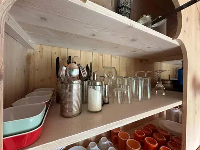 a kitchen shelf with dishes and glasses on it at Glamping - stylová maringotka v srdci Ladova kraje, poblíž hlavního města Prahy in Stříbrná Skalice