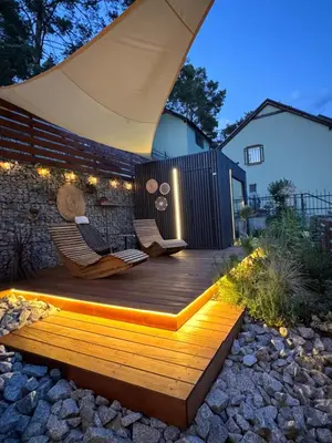 a wooden deck with two chairs and an umbrella at Slapy Chata Hrdlička in Čím