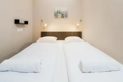 two beds in a small room with white sheets at Minimino hotel in Prague