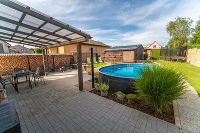 a backyard with a swimming pool and a pergola at Holiday House Adonis in Bystřice